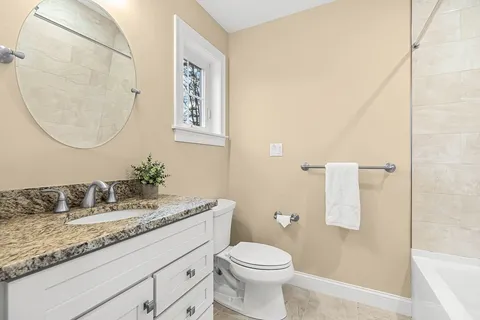 a bathroom with a granite countertop sink a toilet and a mirror