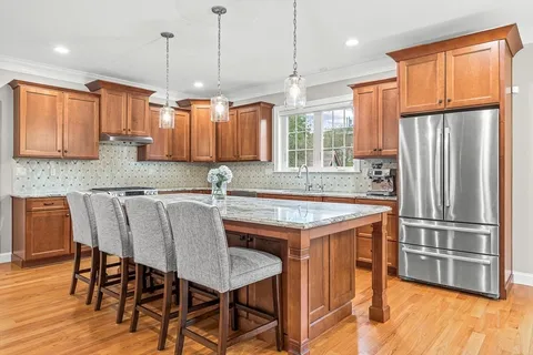 a kitchen with granite countertop a table chairs stainless steel appliances and wooden floor