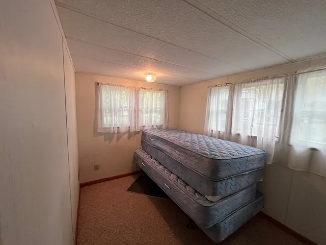 a bed sitting in a spacious bedroom next to a window