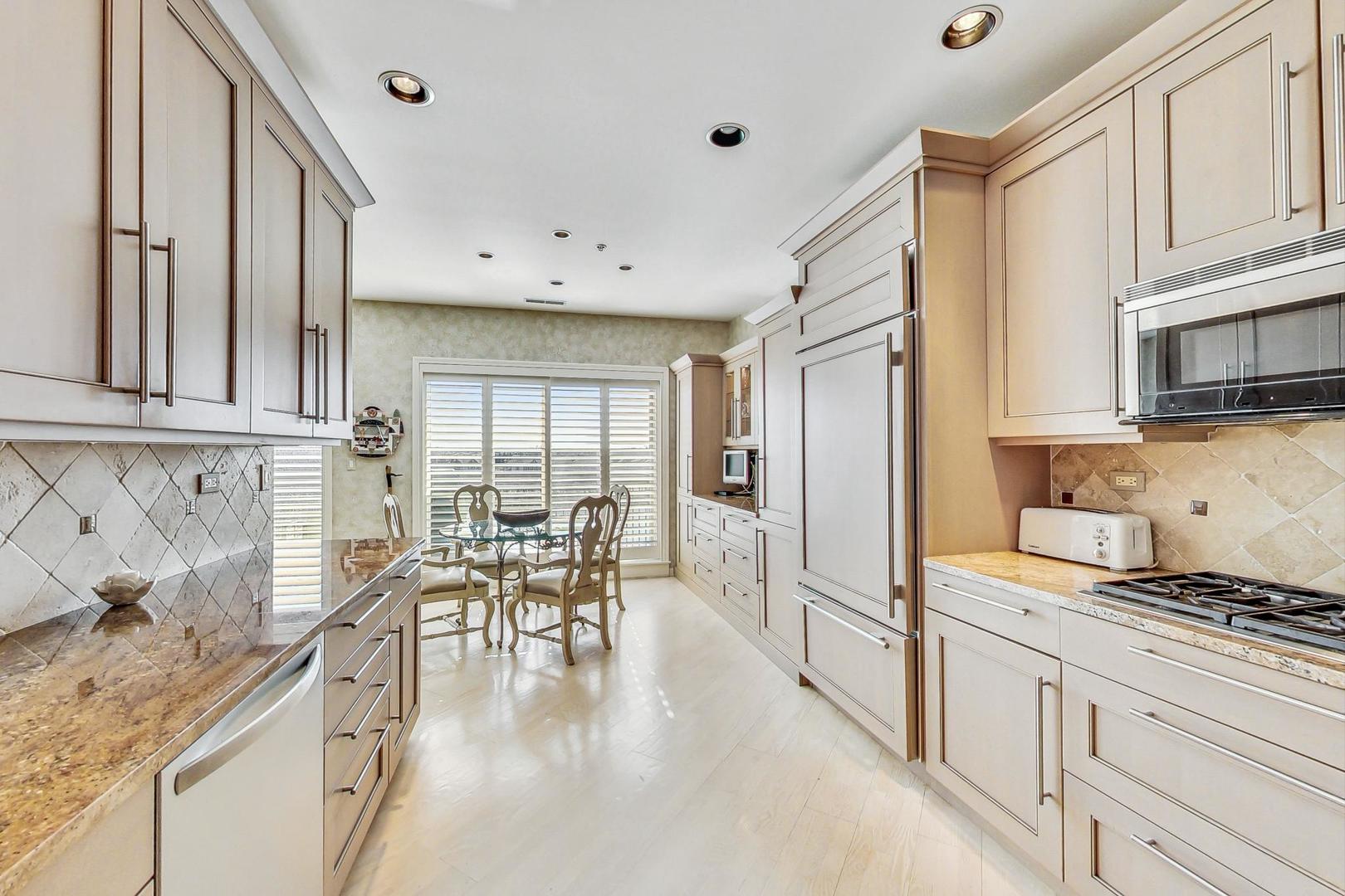 209 Rivershire Lane, Unit 503 Lincolnshire, IL 60069 - Photo 11 of 53 a kitchen with stainless steel appliances granite countertop a stove top oven a sink a dining table and chairs with wooden floor