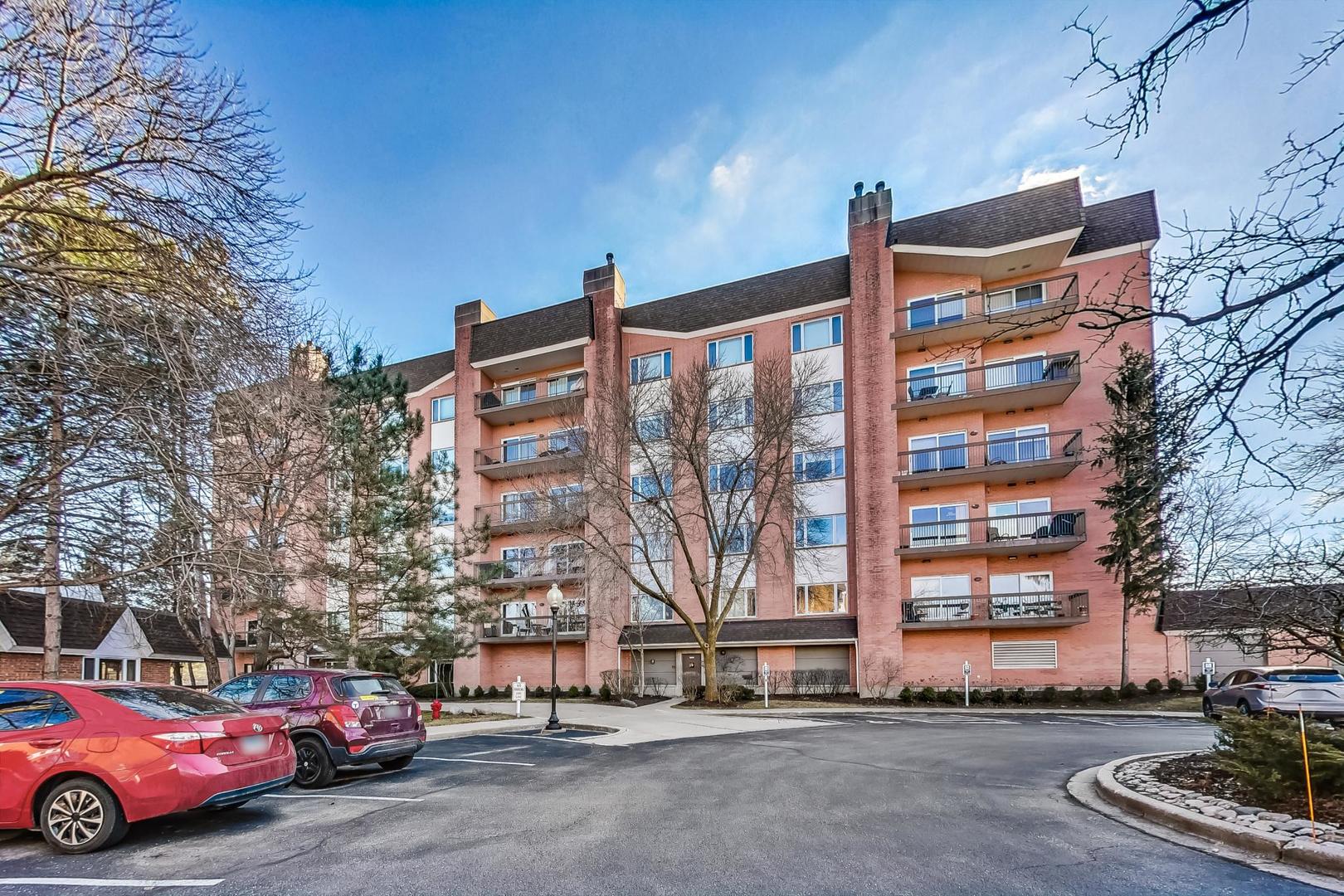 209 Rivershire Lane, Unit 503 Lincolnshire, IL 60069 - Photo 2 of 53 a front view of a building with lot of cars and trees