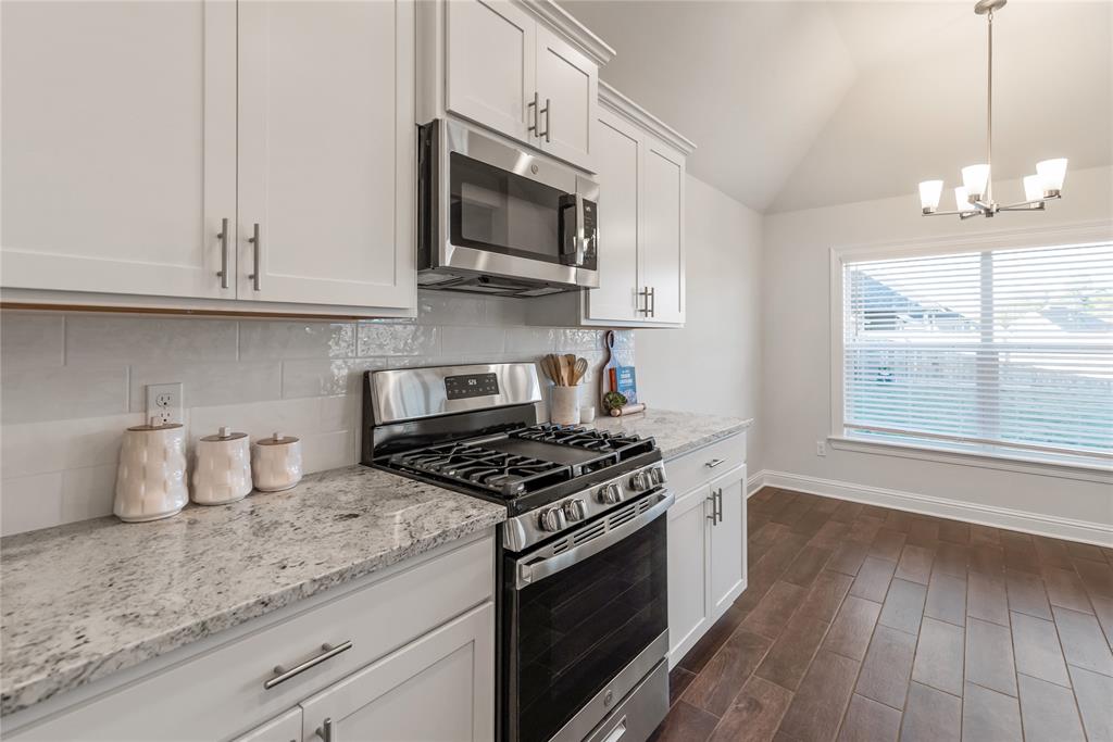 331 Prien Lk Loop Bossier City, LA 71111 - Photo 12 of 37 Kitchen featuring stainless steel appliances, vaulted ceiling, white cabinets, decorative backsplash, and dark wood-style floors