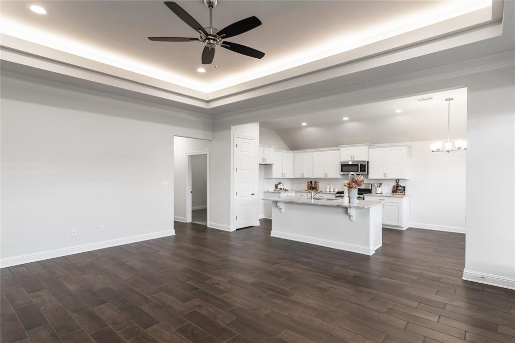331 Prien Lk Loop Bossier City, LA 71111 - Photo 9 of 37 Kitchen with a kitchen breakfast bar, white cabinets, light stone counters, a tray ceiling, and recessed lighting