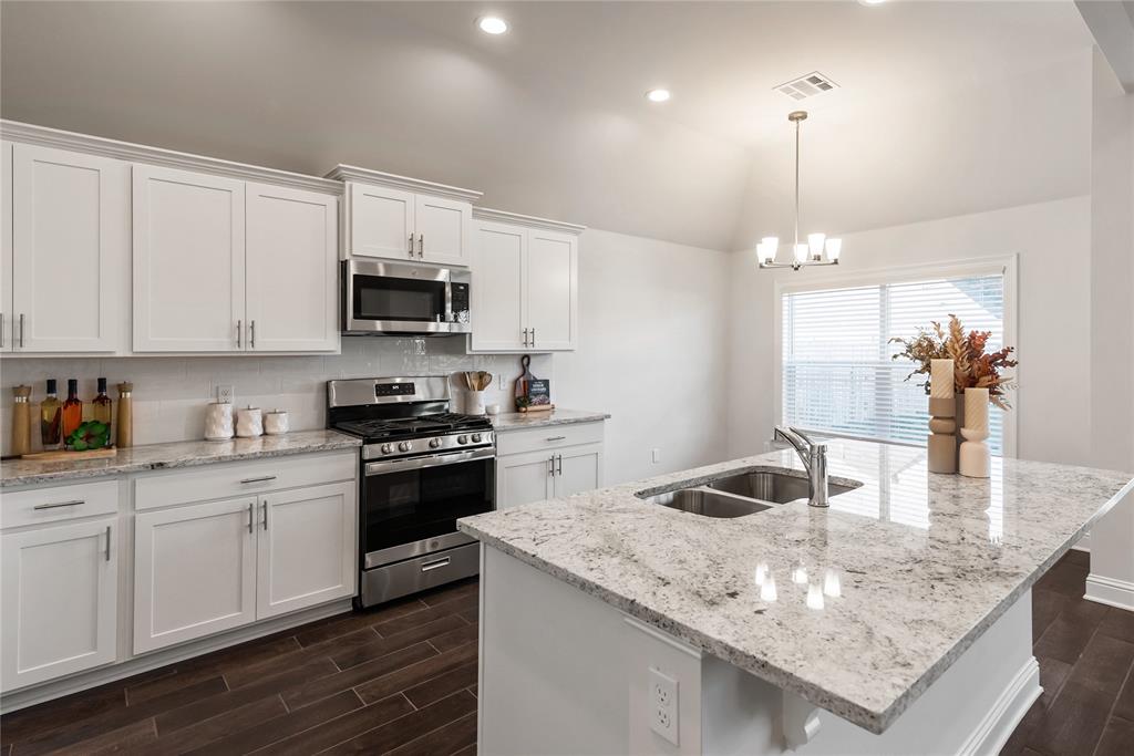 331 Prien Lk Loop Bossier City, LA 71111 - Photo 10 of 37 Kitchen featuring appliances with stainless steel finishes, wood finish floors, white cabinets, tasteful backsplash, and light stone counters