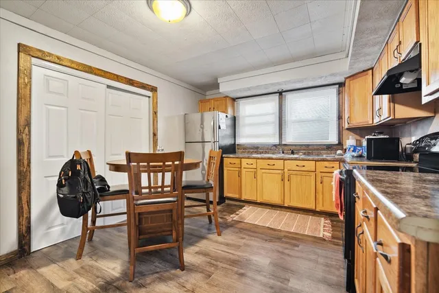 a kitchen with granite countertop a stove a sink and a refrigerator