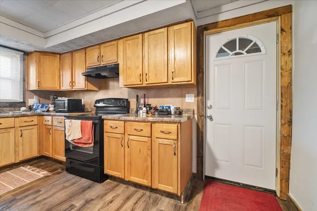 a kitchen with stainless steel appliances granite countertop a refrigerator a sink dishwasher and wooden cabinets with wooden floor