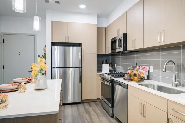a kitchen with kitchen island granite countertop a sink cabinets stainless steel appliances and a counter top space
