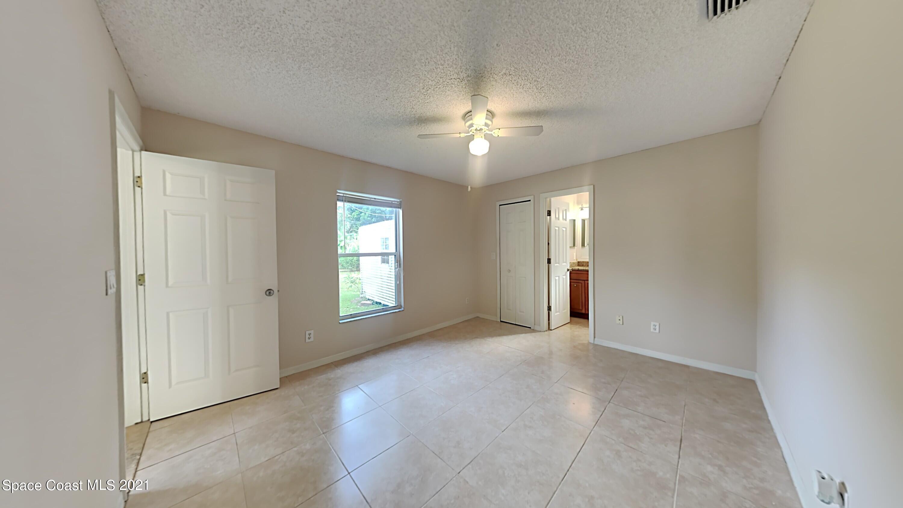 1327 Whitehurst Road Southwest Palm Bay, FL 32908 - Photo 11 of 21 a view of an empty room with chandelier fan and windows