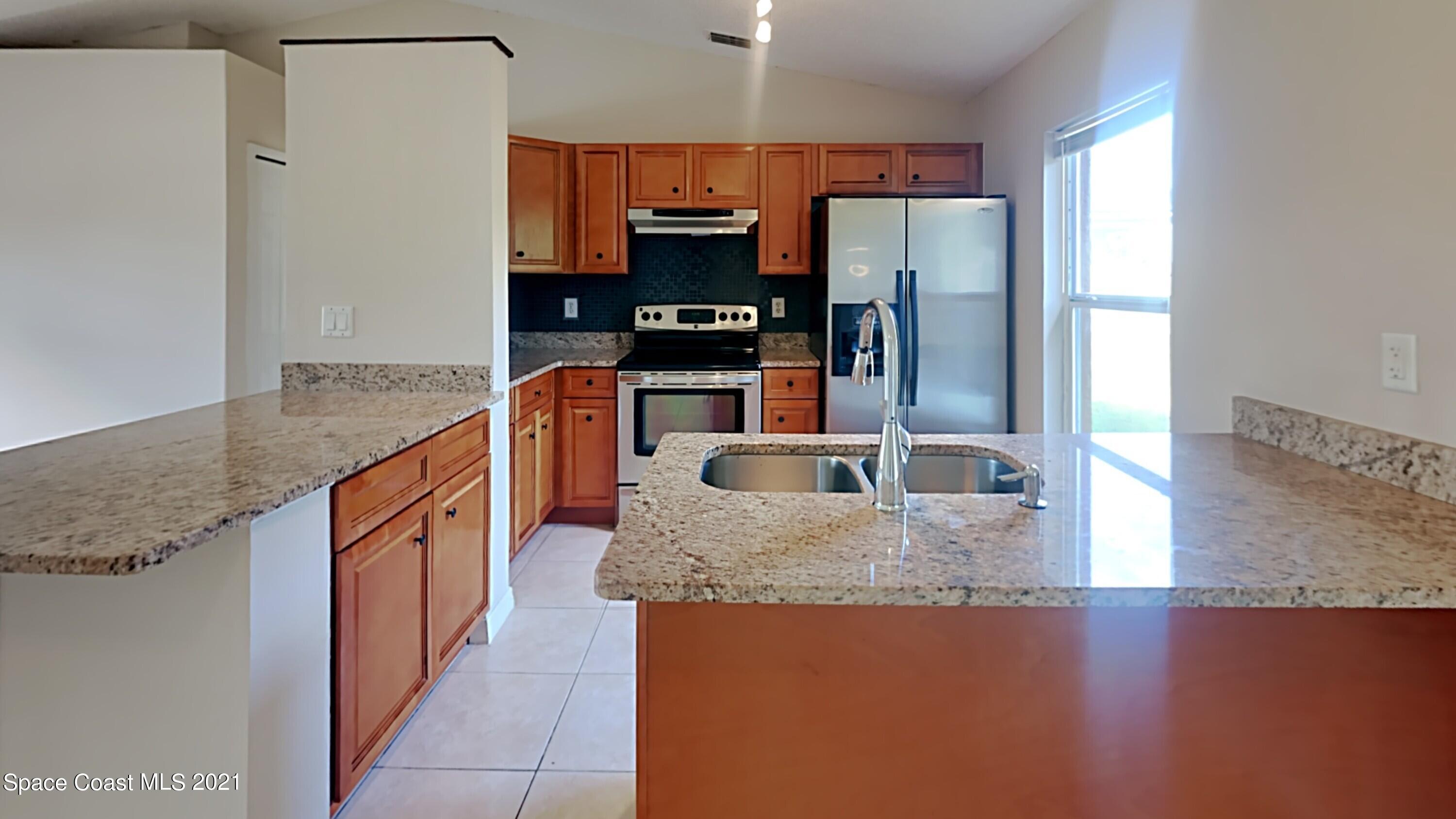 1327 Whitehurst Road Southwest Palm Bay, FL 32908 - Photo 7 of 21 a kitchen with stainless steel appliances granite countertop a refrigerator a stove and a sink with wooden floor