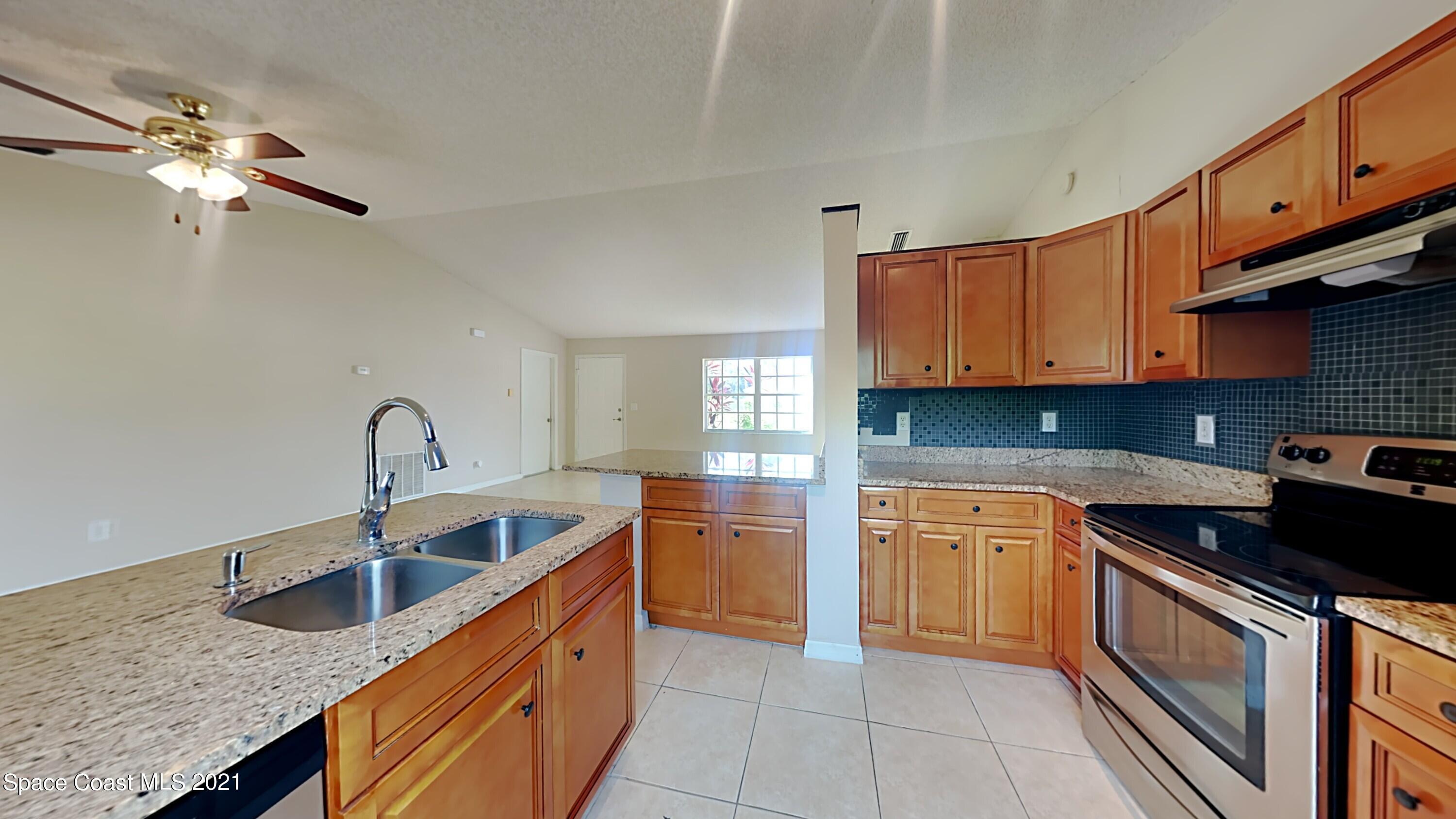 1327 Whitehurst Road Southwest Palm Bay, FL 32908 - Photo 8 of 21 a kitchen with stainless steel appliances granite countertop a sink a stove and a wooden floors