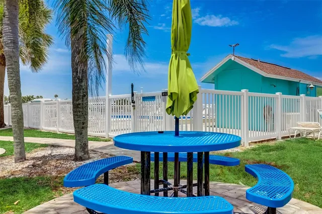 a view of a backyard with table and chairs potted plants and palm tree