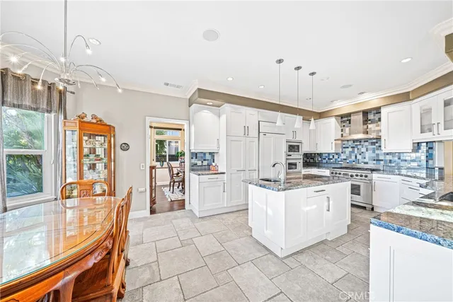 a kitchen with stainless steel appliances a stove a sink dishwasher a refrigerator and white cabinets with wooden floor