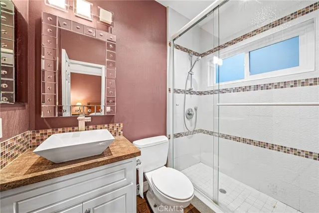 a bathroom with a granite countertop sink toilet mirror and shower