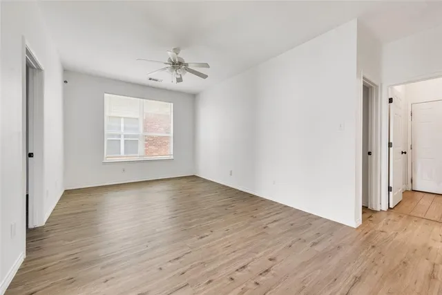 an empty room with wooden floor chandelier and windows