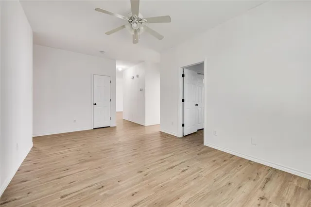 an empty room with wooden floor and ceiling fan