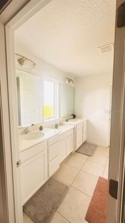 3166 Armstrong Spring Drive Kissimmee, FL 34744 - Photo 29 of 30 a large white bathroom with a double vanity sink a mirror and a bathtub