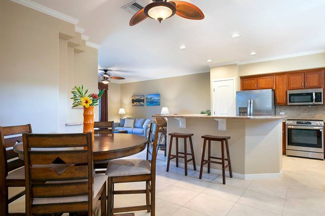 a kitchen with stainless steel appliances kitchen island granite countertop a table chairs and a refrigerator