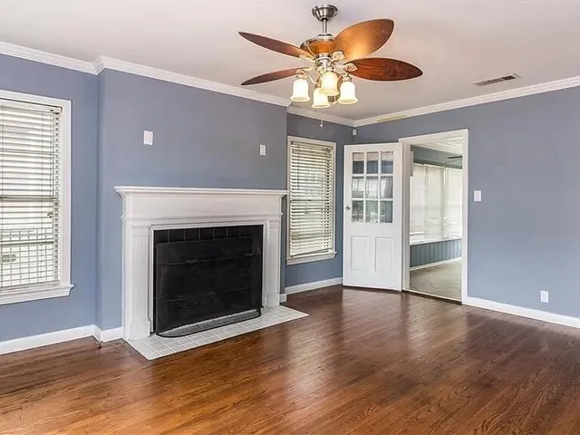 an empty room with wooden floor a ceiling fan and a fireplace