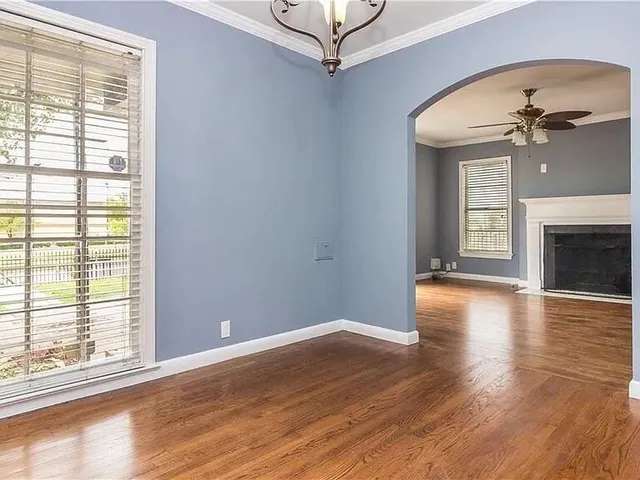 an empty room with wooden floor fireplace and windows