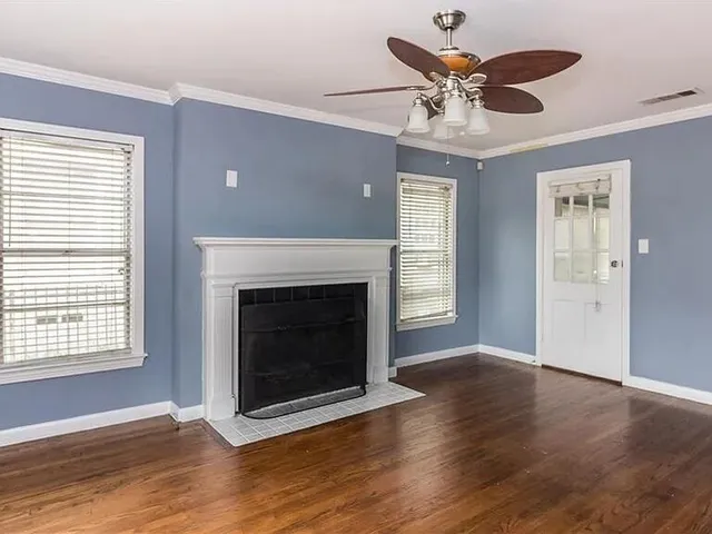 a view of an empty room with wooden floor and a fireplace