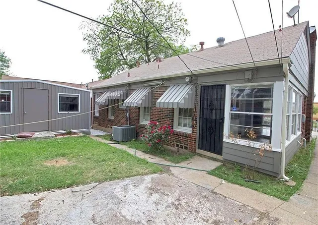 a view of a house with a small yard and a large tree