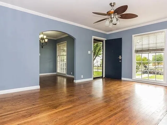 a view of an empty room with window and wooden floor