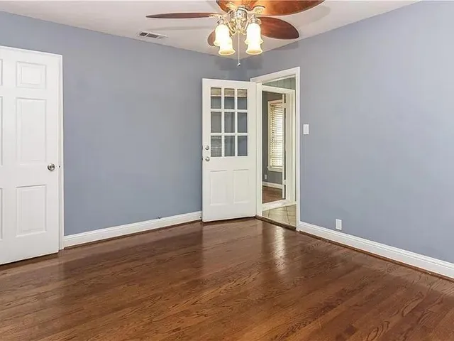 a view of an empty room with wooden floor and a window