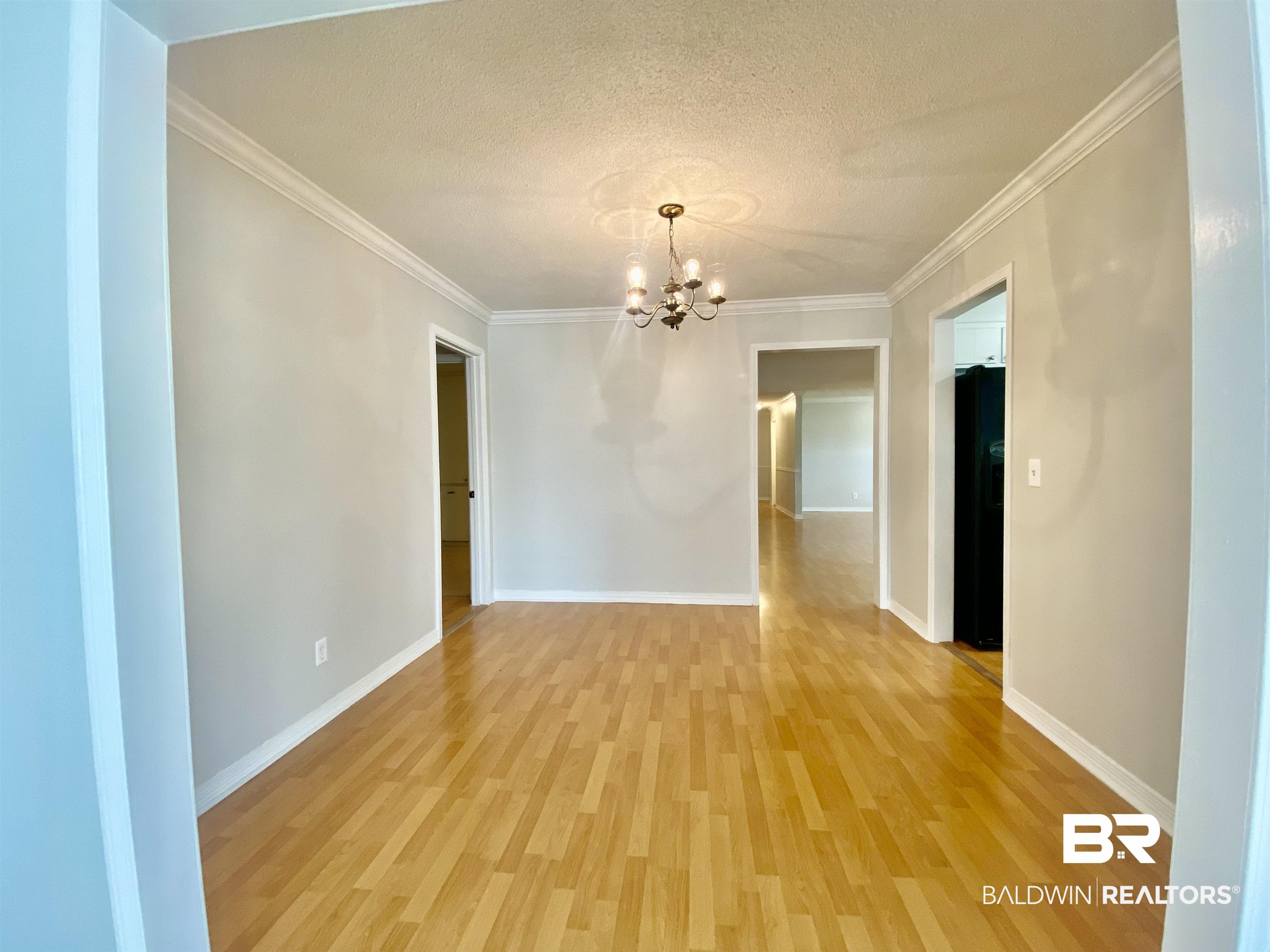 265 Azalea Drive Monroeville, AL 36460 - Photo 12 of 39 Spare room with light hardwood / wood-style floors, a chandelier, a textured ceiling, and crown molding