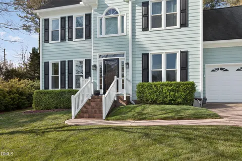 a view of a white house with a yard and large trees