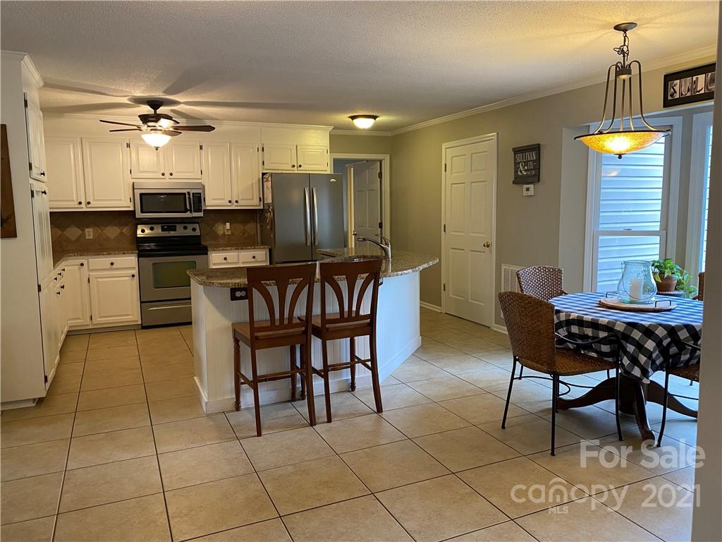 1507 Melchor Road Albemarle, NC 28001 - Photo 5 of 20 a kitchen with stainless steel appliances kitchen island granite countertop a table and chairs in it