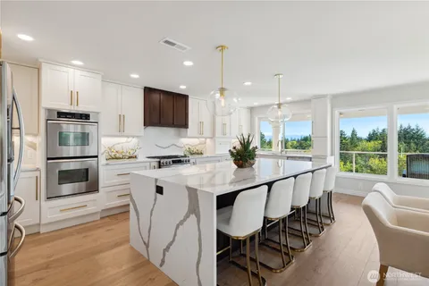 a kitchen with stainless steel appliances kitchen island granite countertop a stove a sink a refrigerator and white cabinets with wooden floor