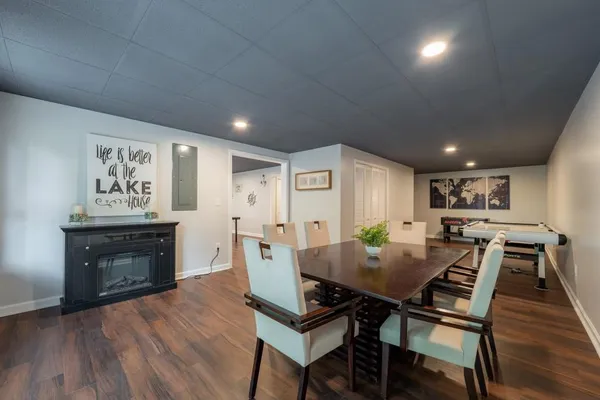 a bedroom with a bed and a lamp on dresser with wooden floor