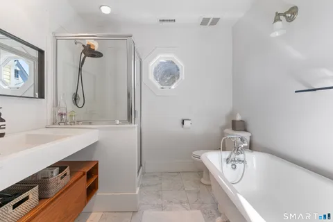 a living room with stainless steel appliances furniture a rug and a window
