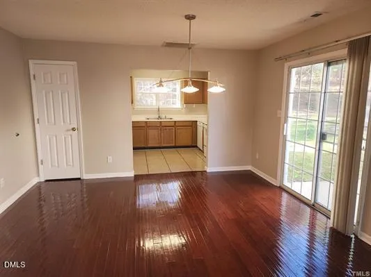 a view of an empty room with window and wooden floor