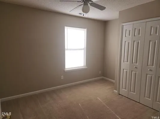 en empty room with windows and chandelier fan