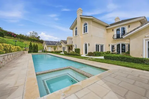 a view of a house with swimming pool lawn chairs and a yard
