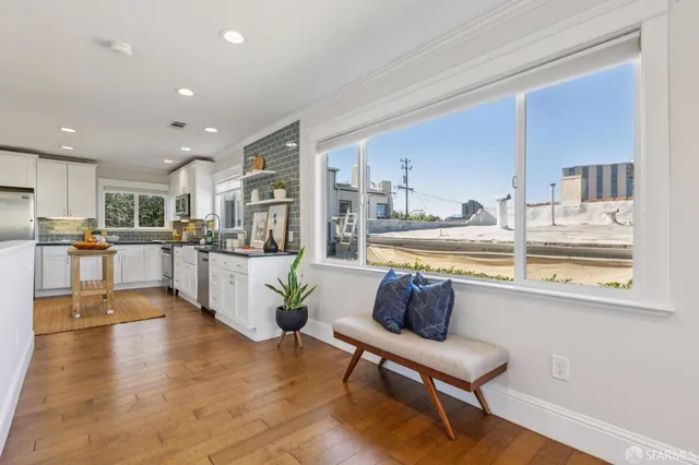 a living room with stainless steel appliances kitchen island granite countertop a refrigerator a stove a sink a dining table and chairs with wooden floor