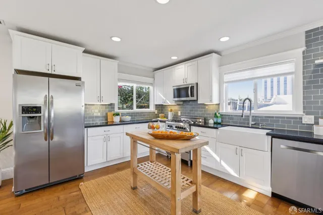 a kitchen with stainless steel appliances granite countertop a sink stove refrigerator and cabinets