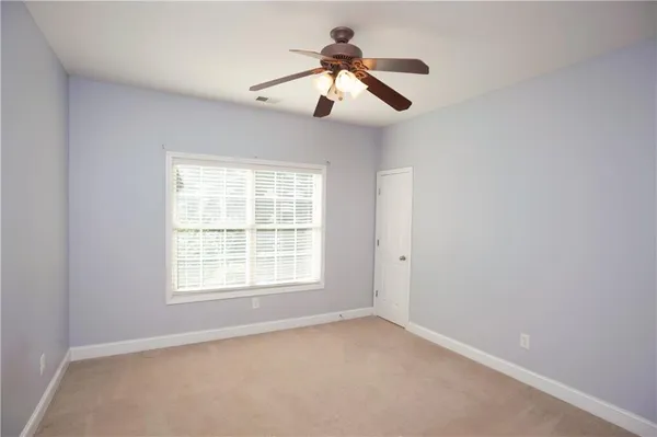 an empty room with chandelier fan and windows
