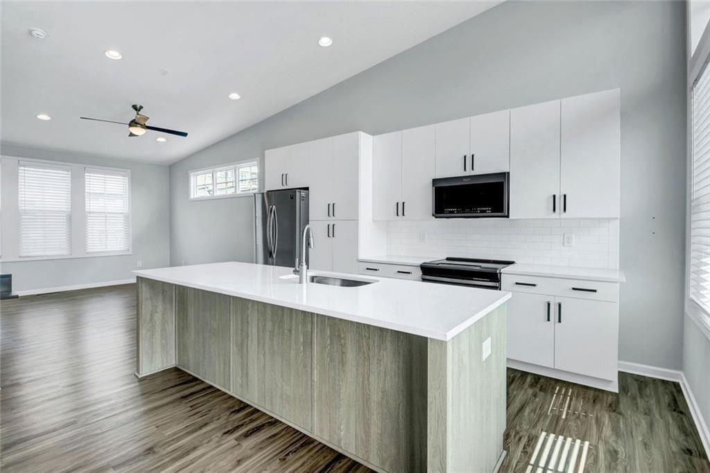 900 Brees Court Atlanta, GA 30318 - Photo 11 of 33 a kitchen with stainless steel appliances a stove top oven a sink dishwasher a refrigerator with wooden floor and cabinets