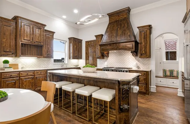 a kitchen with stainless steel appliances granite countertop a kitchen island hardwood floor sink stove dining table and chairs