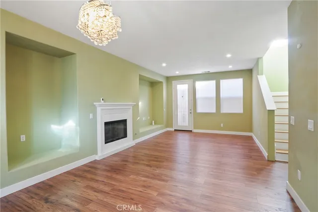 an empty room with wooden floor a fireplace and chandelier