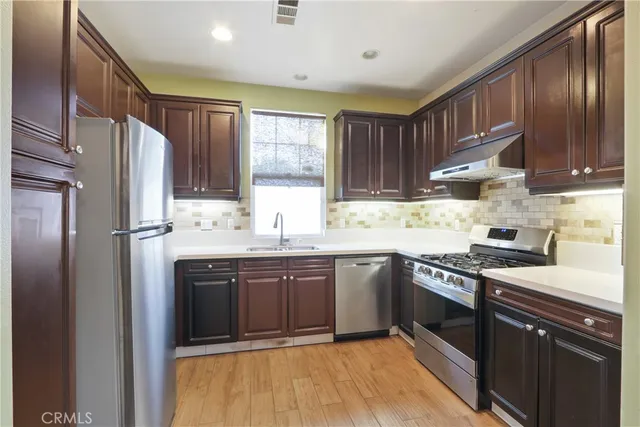 a kitchen with stainless steel appliances granite countertop a stove refrigerator sink and cabinets