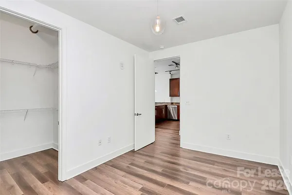 a view of a hallway with wooden floor and a bathroom