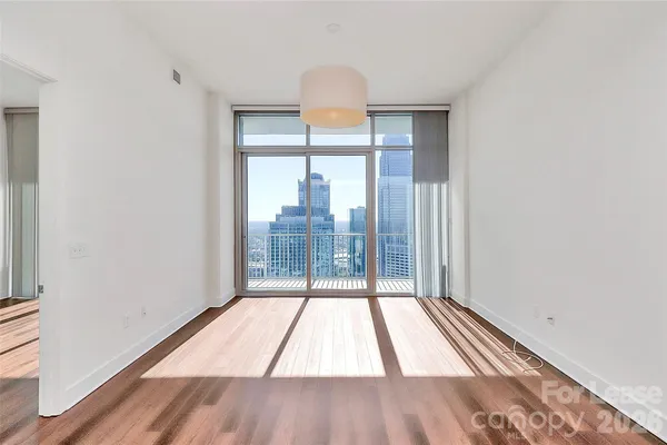 a view of empty room with wooden floor and fan