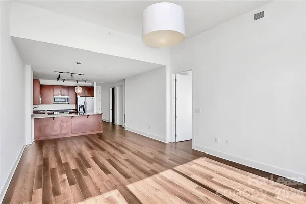 a large living room with kitchen island stainless steel appliances wooden floor and living room view