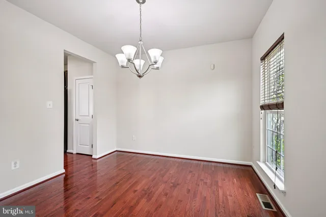 a view of empty room with wooden floor and window