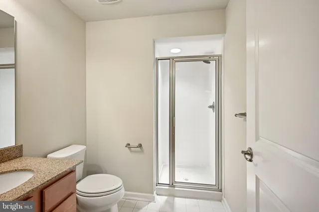 a bathroom with a granite countertop toilet a sink and shower