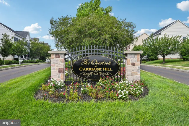 a sign board with flower plants and wooden fence