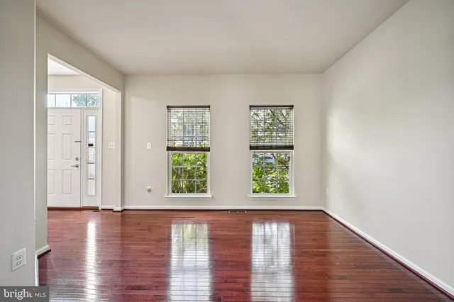a view of an empty room with wooden floor and window
